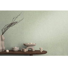 Dekorativ scen med vas, grenar och diverse föremål på ett bord framför en vägg