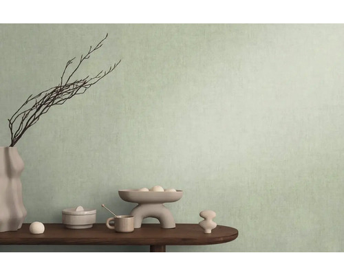 Dekorativ scen med vas, grenar och diverse föremål på ett bord framför en vägg