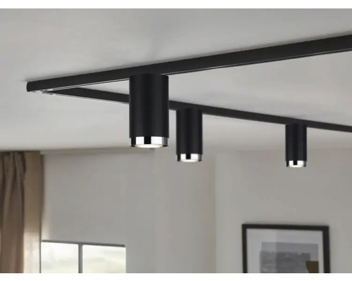 Svart skensystem med tre cylindriska spotlights i taket