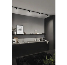 Modernt kök med svarta köksskåp, diskho, hylla och svart skensystem med spotlights.