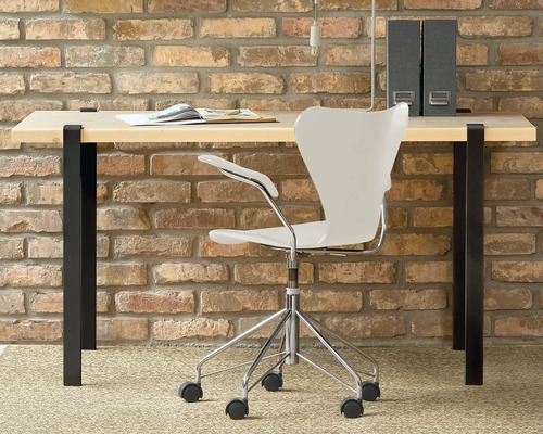 Arbetsrum med skrivbord, kontorsstol och mappar mot en tegelvägg