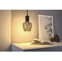 Dekorativ hänglampa ovanför ett nattduksbord med en öppen bok och en inramad bild