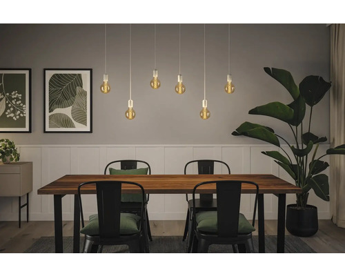 Matsal med träbord, stolar och pendellampor med glödlampor