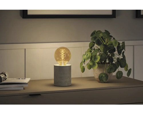 Scen med bordslampa och krukväxt på ett nattduksbord