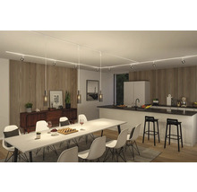 Matsal och kök med belysningssystem i taket, matbord med stolar, skänk och pentry