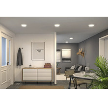 Ljust vardagsrum med infällda taklampor, byrå och matplats