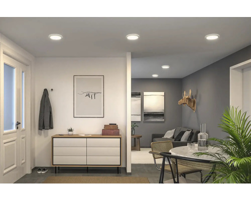 Ljust vardagsrum med infällda taklampor, byrå och matplats