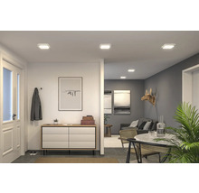 Belyst vardagsrum med taklampor, byrå och dekoration