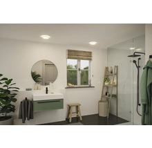 Ljust badrum med tvättställ, spegel, fönster och dusch