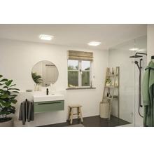 Ljust badrum med tvättställ, spegel, fönster och dusch.