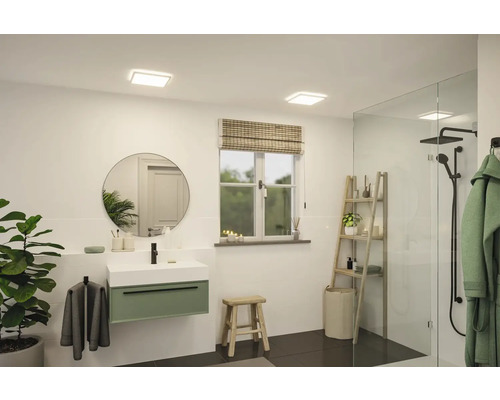 Ljust badrum med tvättställ, spegel, fönster och dusch.