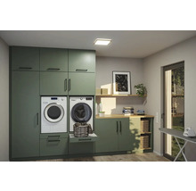 Tvättstuga med tvättmaskin, torktumlare, skåp och strykbräda för hushållsarbete