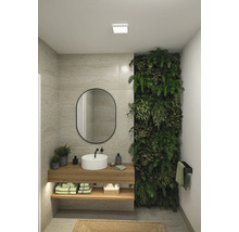 Badrum med tvättställ, spegel, växtvägg och handdukshållare för en naturlig atmosfär