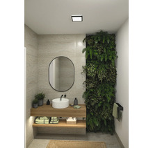 Ljust badrum med handfat, spegel, växtvägg och handdukshängare