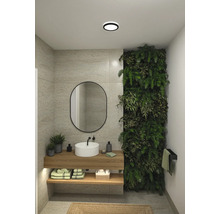 Badrum med handfat, spegel, växtvägg och trähyllor