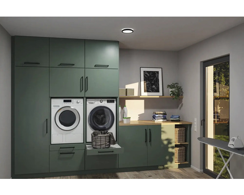 Tvättstuga med tvättmaskin, torktumlare och förvaringslösningar i ett ljust rum.