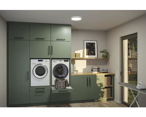 Ljust tvättrum med gröna skåp, tvättmaskin, torktumlare och strykbräda
