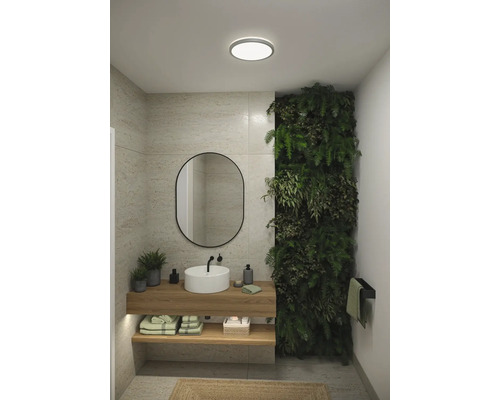 Modernt badrum med handfat, spegel, trähylla och växtvägg