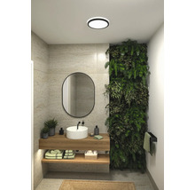 Modernt badrum med handfat, spegel, växtvägg och taklampa