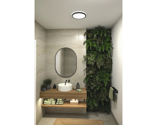 Modernt badrum med handfat, spegel, växtvägg och taklampa