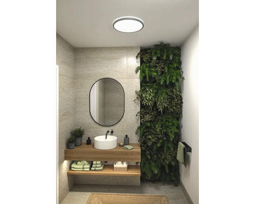 Modernt badrum med tvättställ, spegel, grön vägg och taklampa