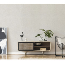 Vardagsrum med byrå, dekorationer, växt och fåtölj.