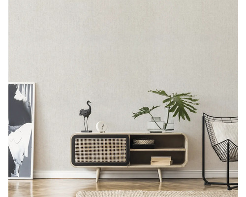 Vardagsrum med byrå, dekorationer, växt och fåtölj.