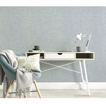 Ljust arbetsrum med skrivbord, stol och lampa mot en strukturerad tapet