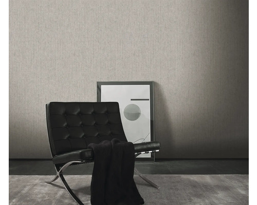 Vardagsrum med en grå strukturtapet, en svart fåtölj och en inramad bild