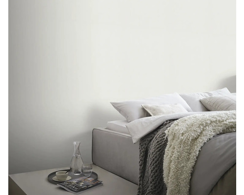 Ljust sovrum med säng, filtar och sidobord