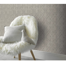 Dekorativt rum med mönstrad tapet och stol med kudde och dekorativ figur