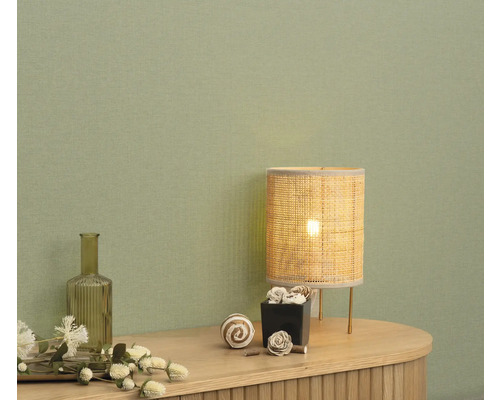 Dekorativ inredning med bordslampa och tillbehör på en byrå framför en vägg.