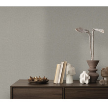 Närbild av en grå strukturtapet ovanför en byrå med dekorativa föremål.