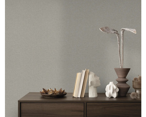 Närbild av en grå strukturtapet ovanför en byrå med dekorativa föremål.