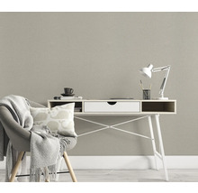 Rumsbild med skrivbord, stol med filt och kudde framför en strukturerad tapet