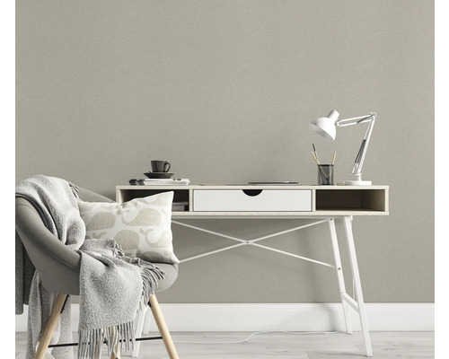 Rumsbild med skrivbord, stol med filt och kudde framför en strukturerad tapet