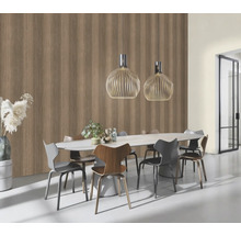 Matsal med matbord, stolar och hänglampor framför en vägg med tapet i träutseende