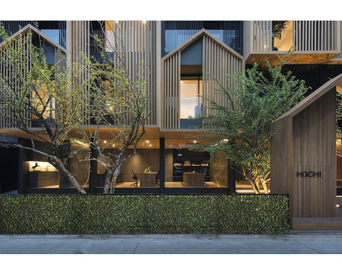 Fasad av en modern byggnad med träpanel och växtlighet