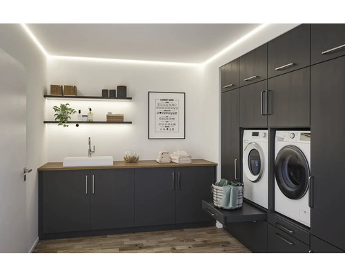 Ljust tvättrum med grå skåp, handfat, tvättmaskiner och hyllor med dekorativa föremål