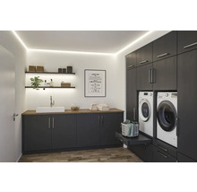 Ljust tvättrum med tvättställ, hyllor och inbyggda skåp med tvättmaskin och torktumlare