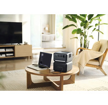 Bärbar kraftstation med bärbar dator på ett bord i ett vardagsrum