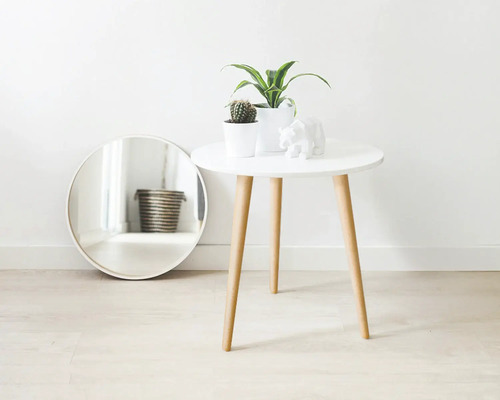 Dekorativ scen med en spegel, ett bord med växter och en björnfigur.