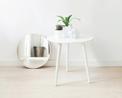 Dekorativ scen med rund spegel, sidobord, krukväxter och skulptur