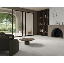 Ljust vardagsrum med klinkergolv, fåtölj, soffbord och vägghylla