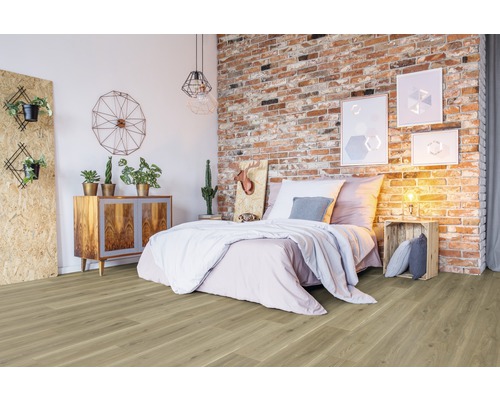 Sovrum med trägolv, säng, byrå och tegelvägg