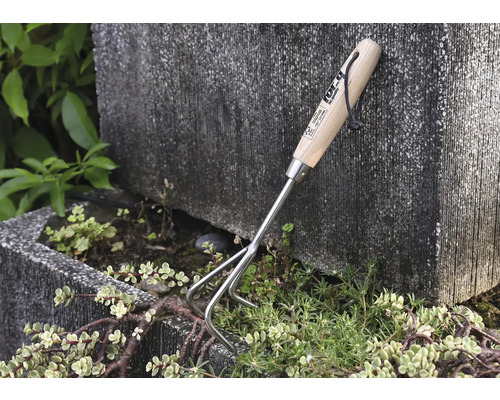 Trädgårdsredskap med trähandtag och tre pinnar för att luckra upp jorden