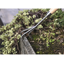 Handräfsa används i en trädgårdsrabatt