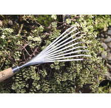 Metallräfsa med trähandtag framför gröna växter