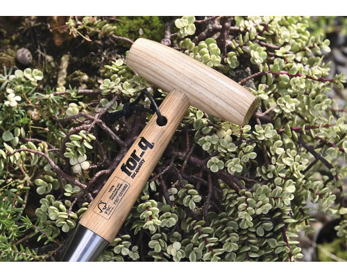 Trädgårdsverktyg med trähandtag och for-q-logotyp, omgiven av växter