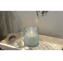 Dekorativt ljus i ett dekorerat glas på en bricka